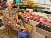 At noon, the rush is over, so this meat vendor is resting her feet.