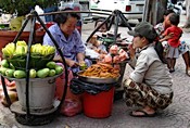 On the street: a vendor of fruit and prawns