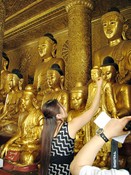 Getting merit by applying gold leaf to a Buddha